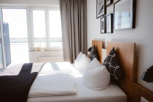 a bedroom with a bed with white sheets and pillows at Hotel Rheinpromenade8 in Emmerich