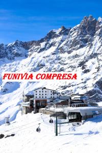 a building in the snow with mountains in the background at Hotel lo Stambecco in Breuil-Cervinia