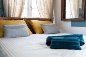 ein weißes Bett mit gelben und blauen Kissen und einem Spiegel in der Unterkunft Ulysse - Charmant T2 dans le Centre de Pont-Audemer in Pont-Audemer