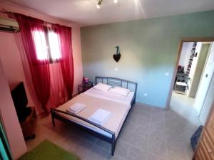 um quarto com uma cama branca e cortinas vermelhas em Little pomegranate apartment em Kapótidhes