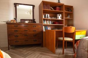 ein Schlafzimmer mit einer Kommode und einem Schreibtisch mit einem Spiegel in der Unterkunft Casa vacanza Oana in SantʼAngelo di Brolo