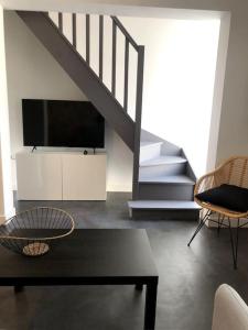 sala de estar con TV, mesa y escaleras en Le 20 La Loire Maison de bord de Loire, en Chalonnes-sur-Loire