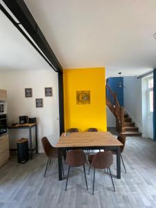 uma sala de jantar com mesa e cadeiras e uma parede amarela em Maison les 3 fées , 3 chambres, Chamerolles em Courcy-aux-Loges