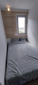 Cama en habitación pequeña con ventana en Home with a view, appartement avec vue panoramique sur la mer, en Ouistreham
