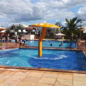 a pool with an umbrella and people in the water at Pousada águas belas in Carolina