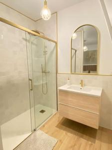 een badkamer met een douche, een wastafel en een spiegel bij L’oasis spa in Quiévrechain