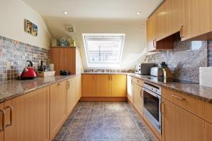 a large kitchen with wooden cabinets and a window at Luna's Seaview Apartment Sleeps 4 Parking Beach in Kent