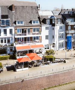 ein Gebäude mit orangefarbenen Sonnenschirmen, Tischen und Gebäuden in der Unterkunft Hotel Rheinpromenade8 in Emmerich