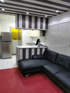 Cloud9 Premium Hostel في دبي: غرفة معيشة مع أريكة سوداء ومطبخ