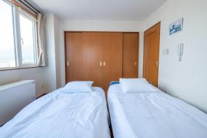 2 Betten in einem kleinen Zimmer mit Fenster in der Unterkunft Ezo Fujiya Niseko House - Vacation STAY 14767 in Kutchan