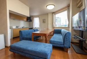 ein Wohnzimmer mit blauen Stühlen und einem Tisch sowie eine Küche in der Unterkunft Ezo Fujiya Niseko House - Vacation STAY 14767 in Kutchan