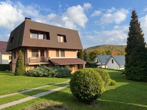 uma casa com um jardim de relva com uma árvore em ubytovanie Vážka em Banská Štiavnica