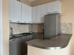 La cuisine est équipée de placards blancs et d'un réfrigérateur en acier inoxydable. dans l'établissement Holiday apartment, à Tbilissi
