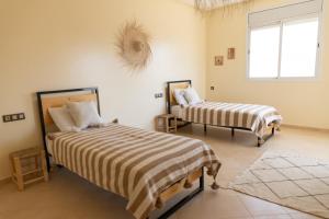 1 Schlafzimmer mit 2 Betten und einem Fenster in der Unterkunft Wavy Days in Tamraght Ouzdar