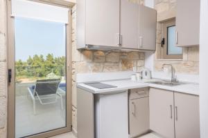 a kitchen with white cabinets and a sliding glass door at Anna Mare Luxury Apartments in Afitos