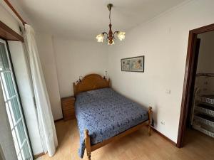 Un dormitorio con una cama y una lámpara de araña. en 100 Meters from the Beach! Rua da Regeneração Nazaré, en Nazaré