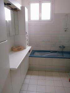 La salle de bains blanche est pourvue d'une baignoire et d'un lavabo. dans l'établissement Les Abricots, à Tarascon