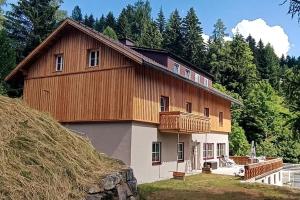 a large wooden house with a deck on a hill at Alpen Apartments Salzburg in Lessach