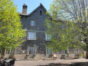 an old stone house with tables and chairs in front of it at L'Eau Berge - Relais Motards - GTMC & Tour des Vaches B&B in Allanche