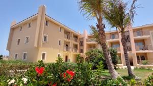 a large apartment building with palm trees and flowers at Sunset house Cabo Verde in Santa Maria