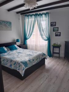 a bedroom with a bed with blue curtains and a window at La Cour in Villefagnan