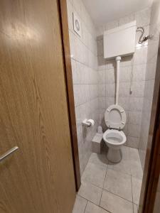 La salle de bains est pourvue de toilettes et d'une porte en bois. dans l'établissement Apartmani Kapiton, à Hvar