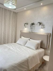 a bedroom with a white bed with white pillows at Studio SvEt 39 in Mohammedia