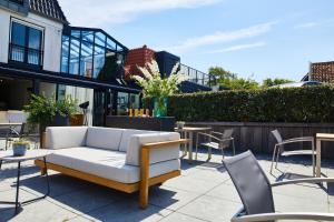 a patio with a couch and tables and chairs at Relaîs & Châteaux Bij Jef in Den Hoorn