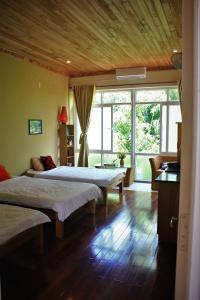 een slaapkamer met 2 bedden en een groot raam bij The HillSide Homestay Hue in Hue