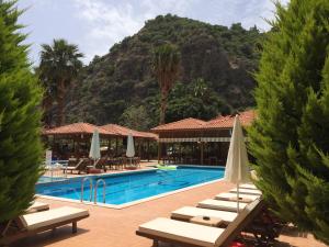 a swimming pool with lounge chairs and a mountain at Hotel Oludeniz in Oludeniz