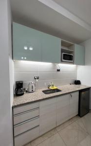 a white kitchen with a sink and a microwave at Monoambiente CENTRICO Neuquén Capital - ESPECTACULAR VISTA in Neuquén