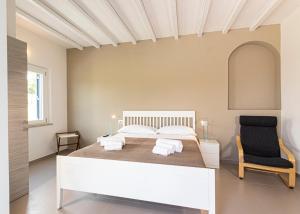 a bedroom with a white bed and a black chair at B&B Villa Costanza in Lacona