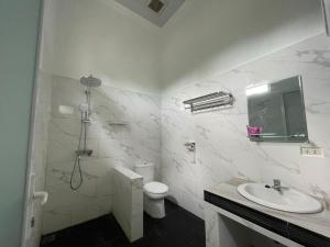 La salle de bains blanche est pourvue de toilettes et d'un lavabo. dans l'établissement PONDOK SAHANG COTTAGES, à Muntok