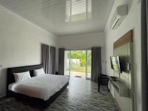 a bedroom with a bed and a flat screen tv at PONDOK SAHANG COTTAGES in Muntok
