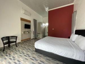 a hotel room with a bed and a chair at PONDOK SAHANG COTTAGES in Muntok