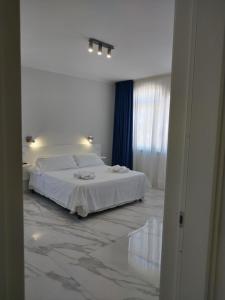 a white bedroom with a bed and a window at Villa Laura Residence Hotel Apartments & Studios in Ascea