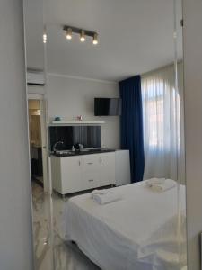 a bedroom with a white bed and a kitchen at Villa Laura Residence Hotel Apartments & Studios in Ascea