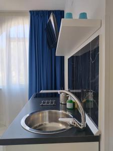 a sink in a kitchen with a blue curtain at Villa Laura Residence Hotel Apartments & Studios in Ascea