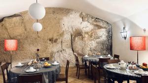 comedor con 2 mesas y pared de piedra en Hotel Palazzo Piccolomini en Orvieto
