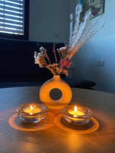 two candles are sitting on a table with a vase at המקום של ענת. Anat's place in Tel ‘Adashim