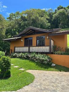 a small yellow house with a garden in front of it at Pousada A Rosa e o Rei in São Francisco Xavier