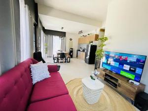ein Wohnzimmer mit einem roten Sofa und einem Flachbild-TV in der Unterkunft Seafront Residences Vacation Getaway in San Juan