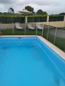 una piscina azul en un patio con sillas y sombrilla en Apartamentos Rial, en Sanxenxo