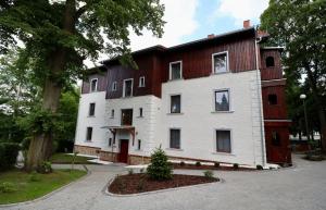 a large white and brown house with a tree at Apartamenty Dębowa 3 in Polanica-Zdrój