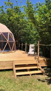 une terrasse en bois avec une chaise et une tente dans l'établissement SIMBIOSIS. Agri Cultur'Art Camp, à Pontinvrea