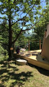 una terraza de madera con un árbol y una tienda de campaña en SIMBIOSIS. Agri Cultur'Art Camp en Pontinvrea