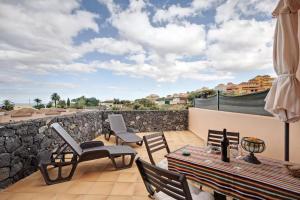un patio con sillas, una mesa y una pared de piedra en Apartamento El Zumacal, en Breña Baja