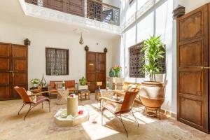 uma grande sala de estar com cadeiras e mesas em Dar Khmissa Riad & Spa em Marrakech