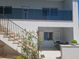 uma casa branca com uma escada e um pátio em Apartman Matea em Topići
