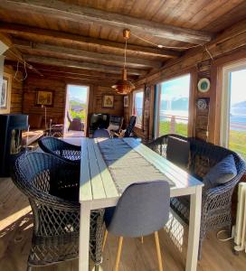 a dining room with a table and chairs and windows at Lyngen Biarnes- Nordreisa in Hamnnes